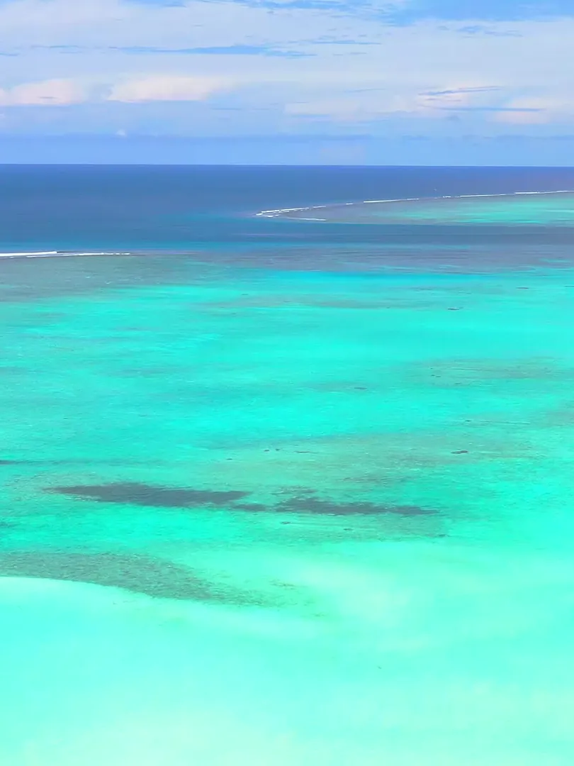 Clear turquoise water over a shallow reef, with the open sea on the horizon